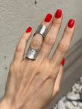 A person's hand wearing a sterling silver full finger ring with a matte finish.