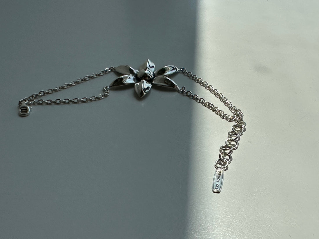 Silver bracelet with floral designs on a gray background