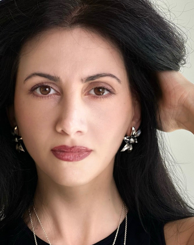 Woman with dark hair and floral earrings, wearing a black top.